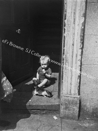 CHILD AT DOORWAY  OF HARDWICKE STREET SLUM WITH KITTEN